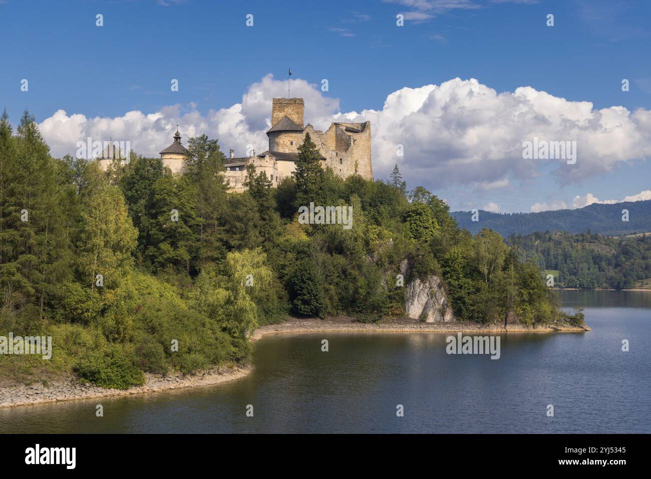 In Niedzica, Polen, liegt das Schloss Dunajec inmitten des ruhigen Wassers und steht stolz vor einem leuchtend blauen Himmel Stockfoto