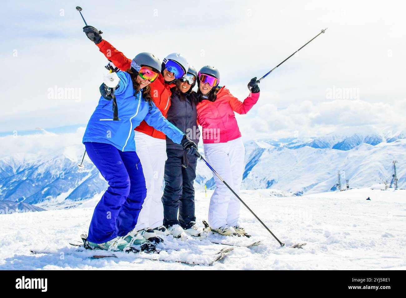 Gudauri, Georgia - 25. januar 2022: Gruppe von vier Mädchen auf Skiern am Aussichtspunkt haben lustige Posen im Skigebiet Winter Snow Mountain lächelnde Freunde nehmen Stockfoto