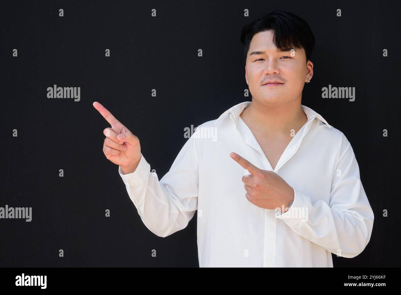 Porträt eines gutaussehenden jungen asiatischen Mannes vor schwarzem Hintergrund Stockfoto