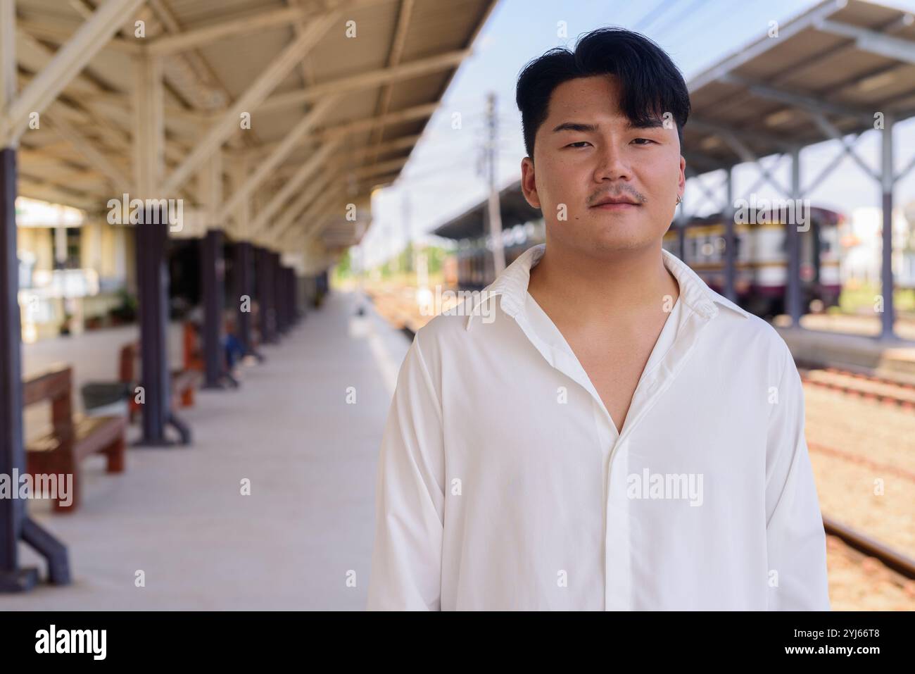 Porträt eines hübschen jungen asiatischen Mannes im Freien, der auf das Zugkonzept wartet Stockfoto