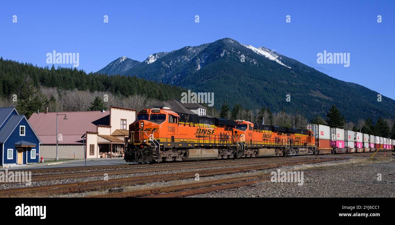 Skykomish, WA, USA - 6. November 2024; BNSF-intermodaler Güterzug fährt über Skykomish und schneebedeckten Gipfel Stockfoto