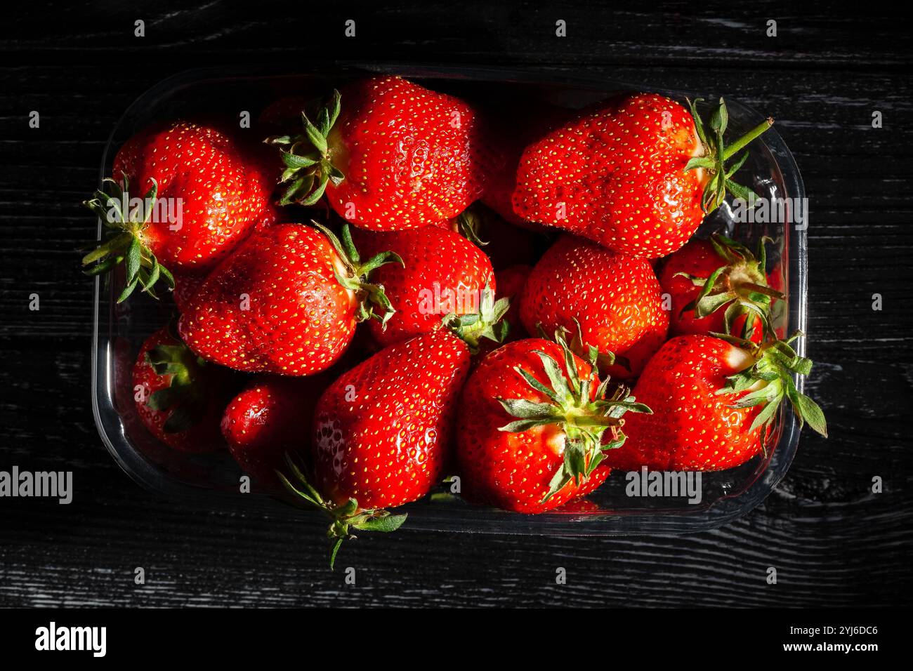 Erdbeerpaket auf schwarzem Holzhintergrund, Draufsicht Stockfoto
