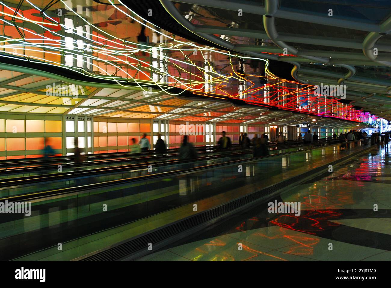 Passagiere, die sich zwischen den Terminals am Chicago O'Hare International Airport bewegen, laufen unter einem farbenfrohen Neonlicht über dem People Mover Stockfoto
