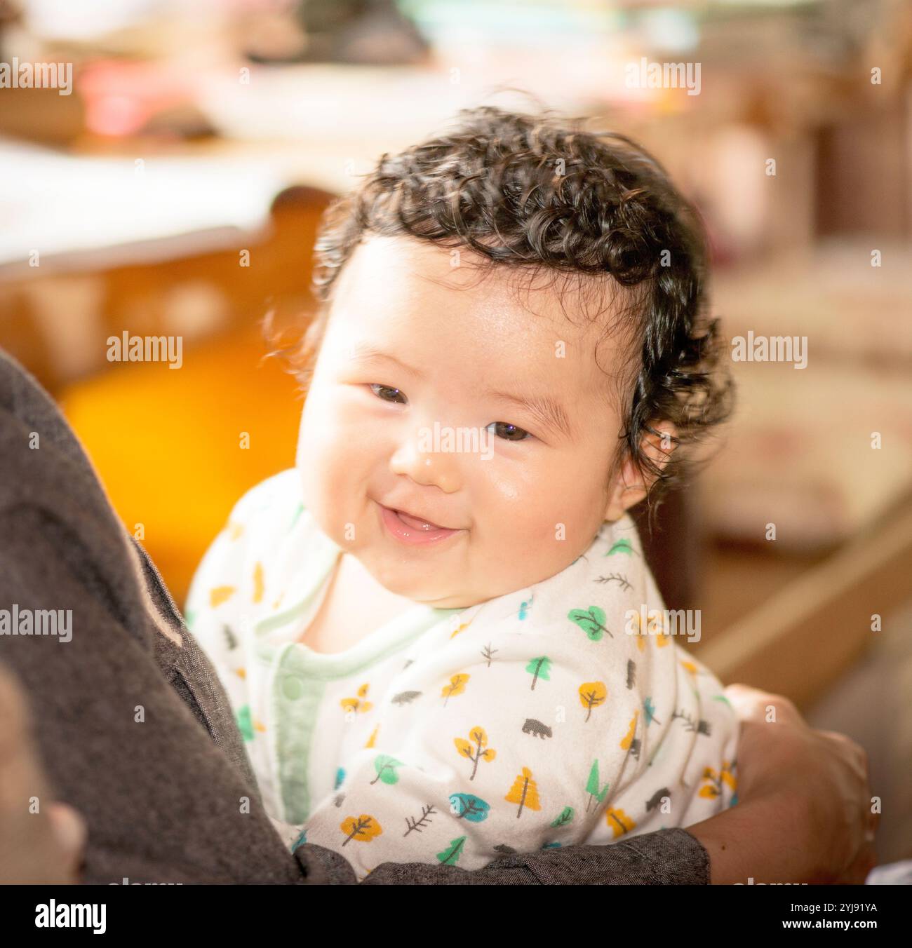 Ein lächelndes viermonatiges Baby, das von ihrer Mutter gehalten wird Stockfoto