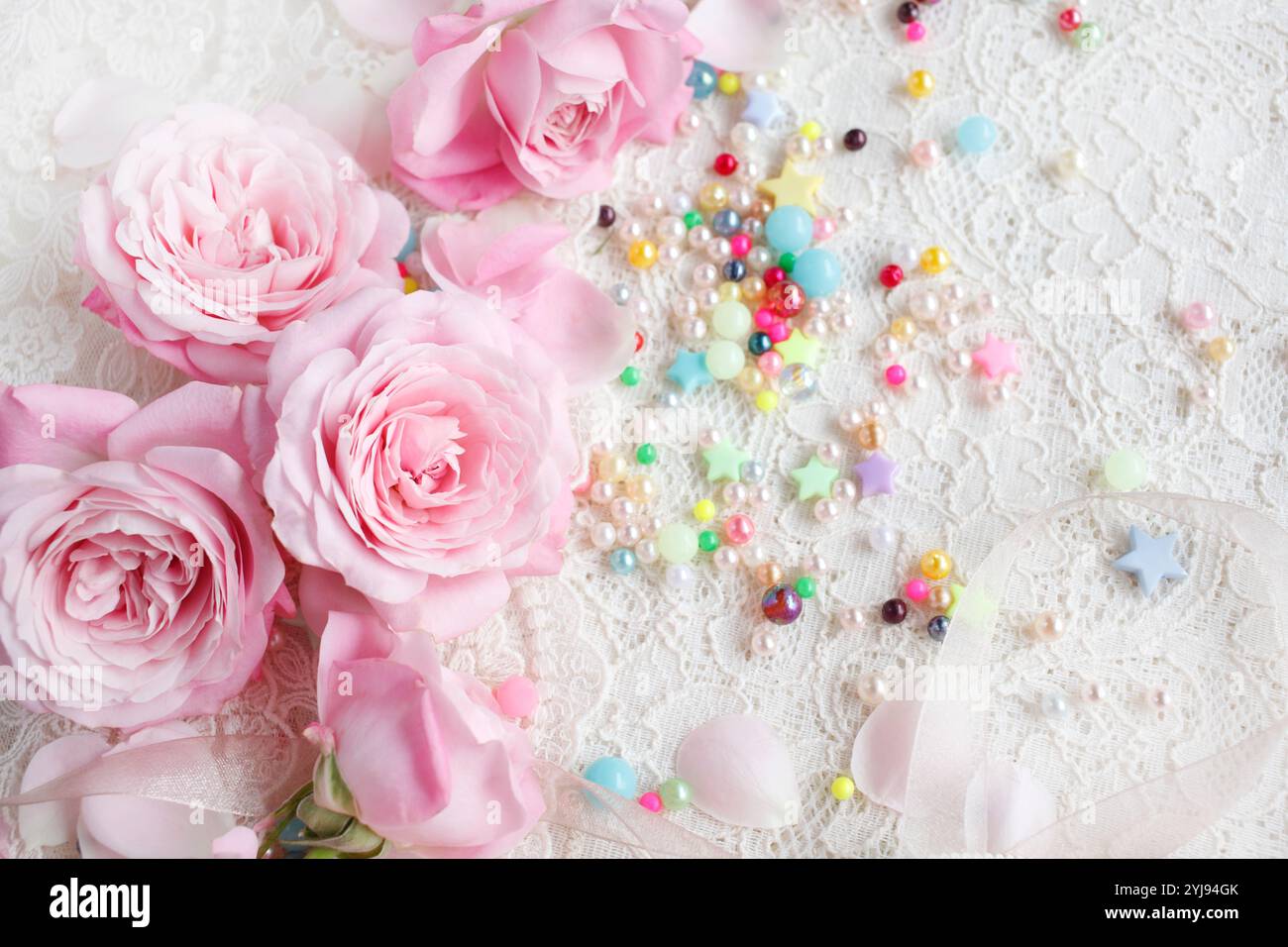Rosa Rosenblüten und verstreute bunte Perlen Stockfoto