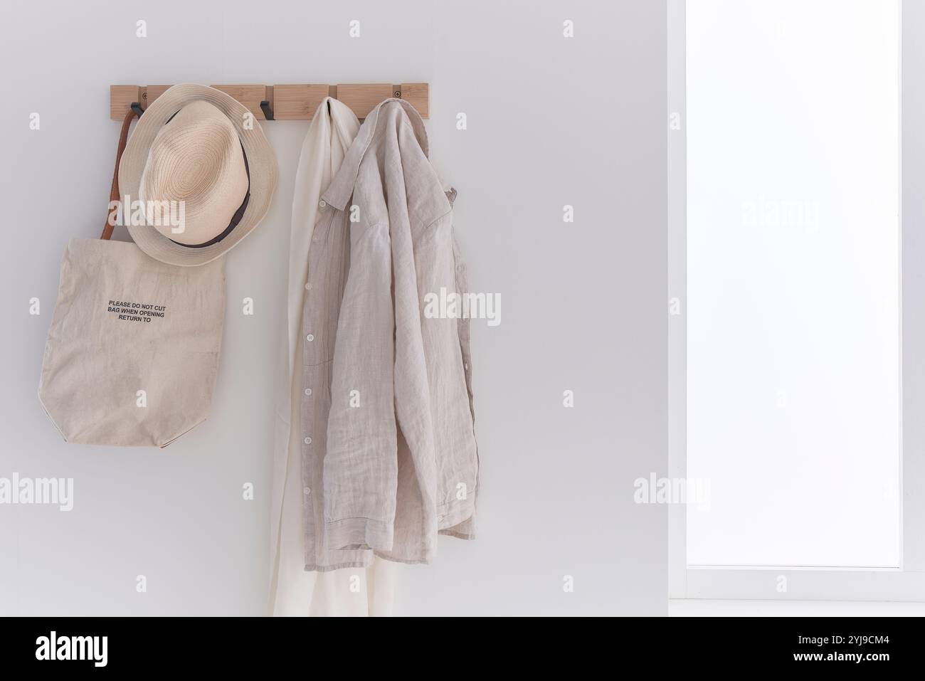 Hemden, Hüte und Taschen hängen an Wandhaken Stockfoto