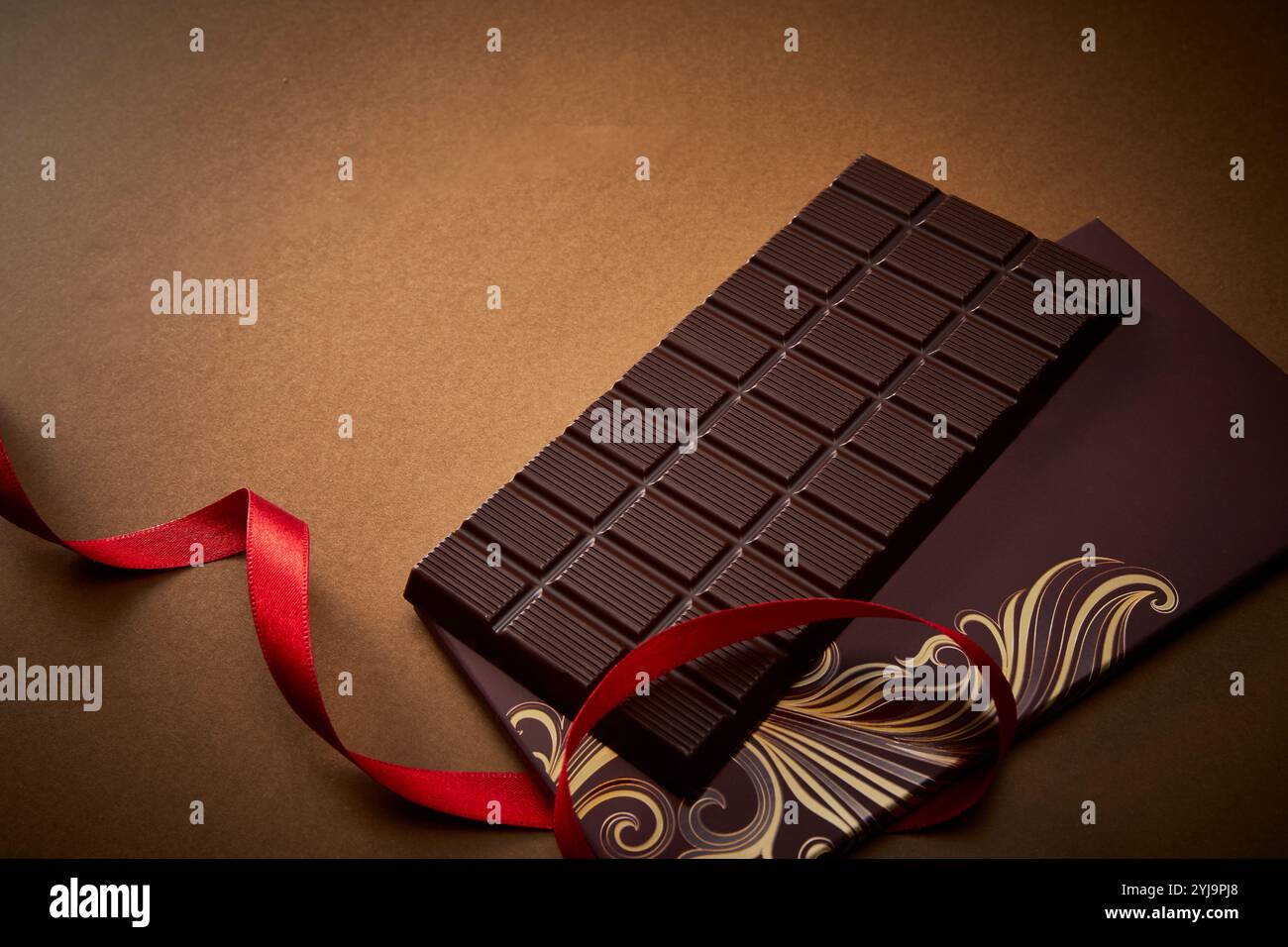 Schokoladentafel mit rotem Band auf goldenem Hintergrund Stockfoto