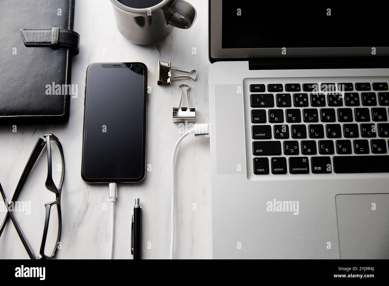 Laptop, Smartphone und Zubehör auf einem Tisch mit Marmorplatte Stockfoto