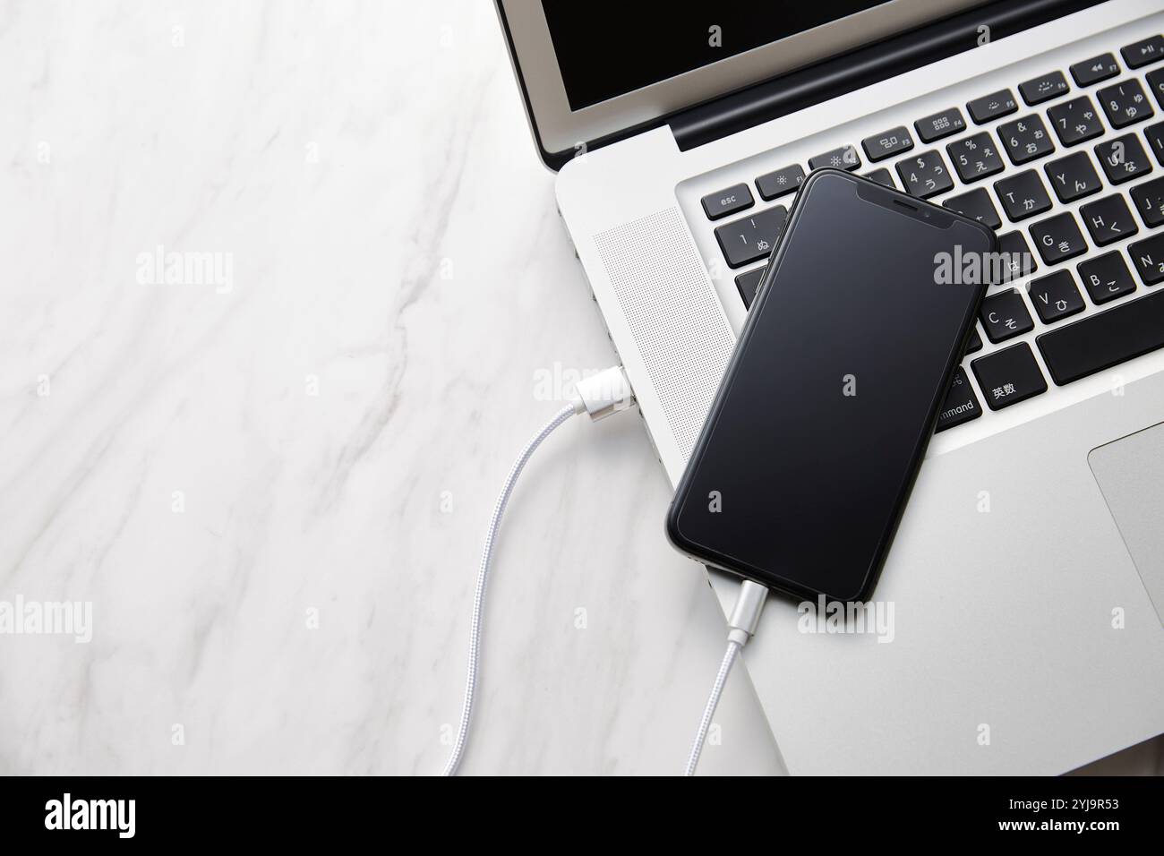 Laptop, Smartphone und Zubehör auf Tischplatte mit Marmorplatte Stockfoto