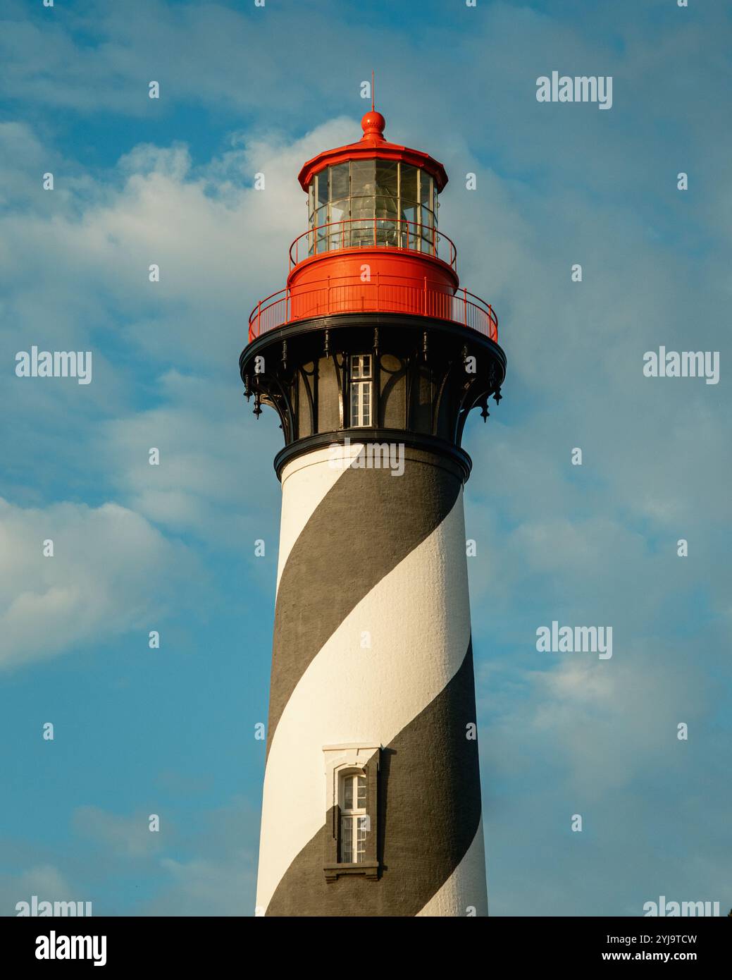 Ein hoch aufragender schwarz-weiß gestreifter Leuchtturm mit roter Spitze vor blauem Himmel, im St. Augustine Lighthouse & Maritime Museum, St. August Stockfoto