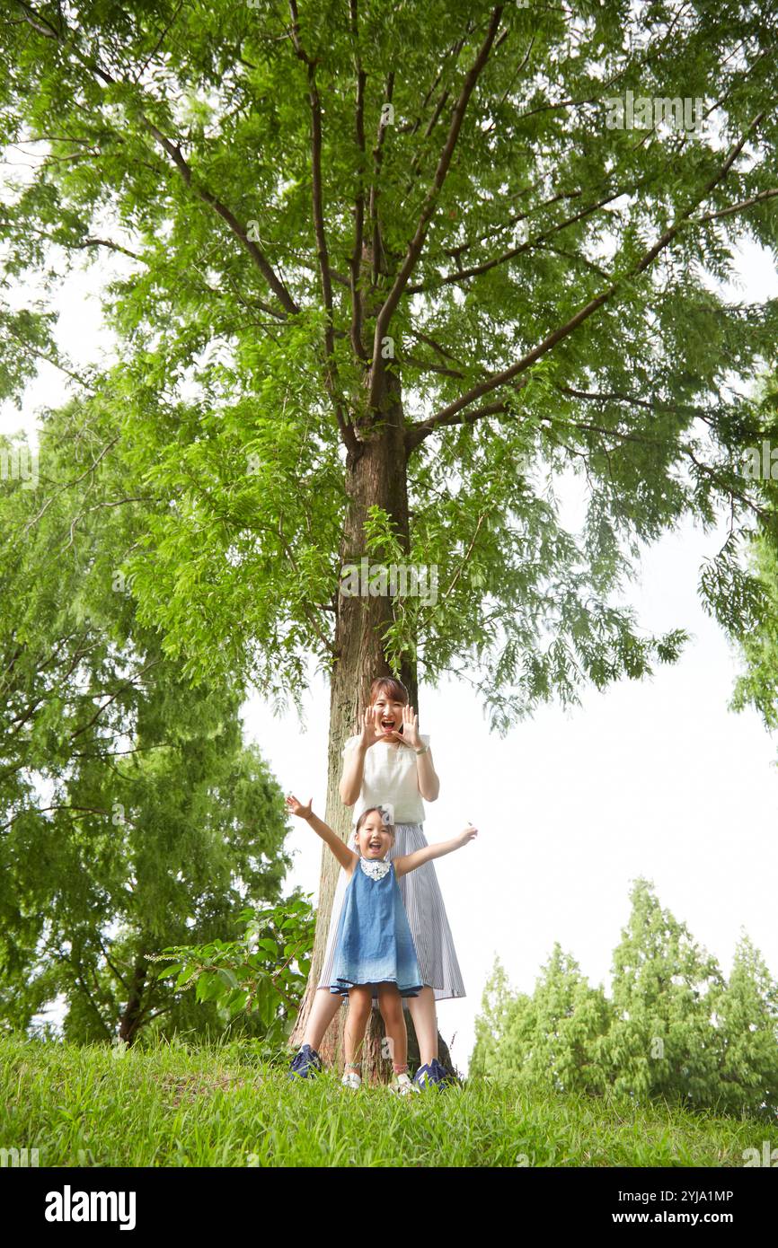 Mutter und Mädchen schreien vor einem Baum im Park Stockfoto