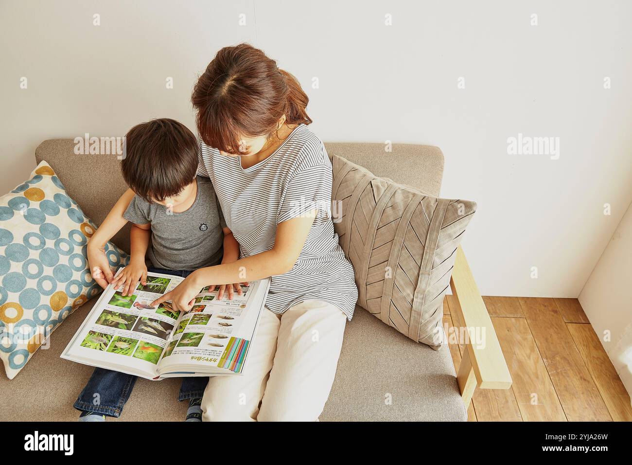 Eltern und Kind schauen sich ein Bilderbuch auf dem Sofa an Stockfoto