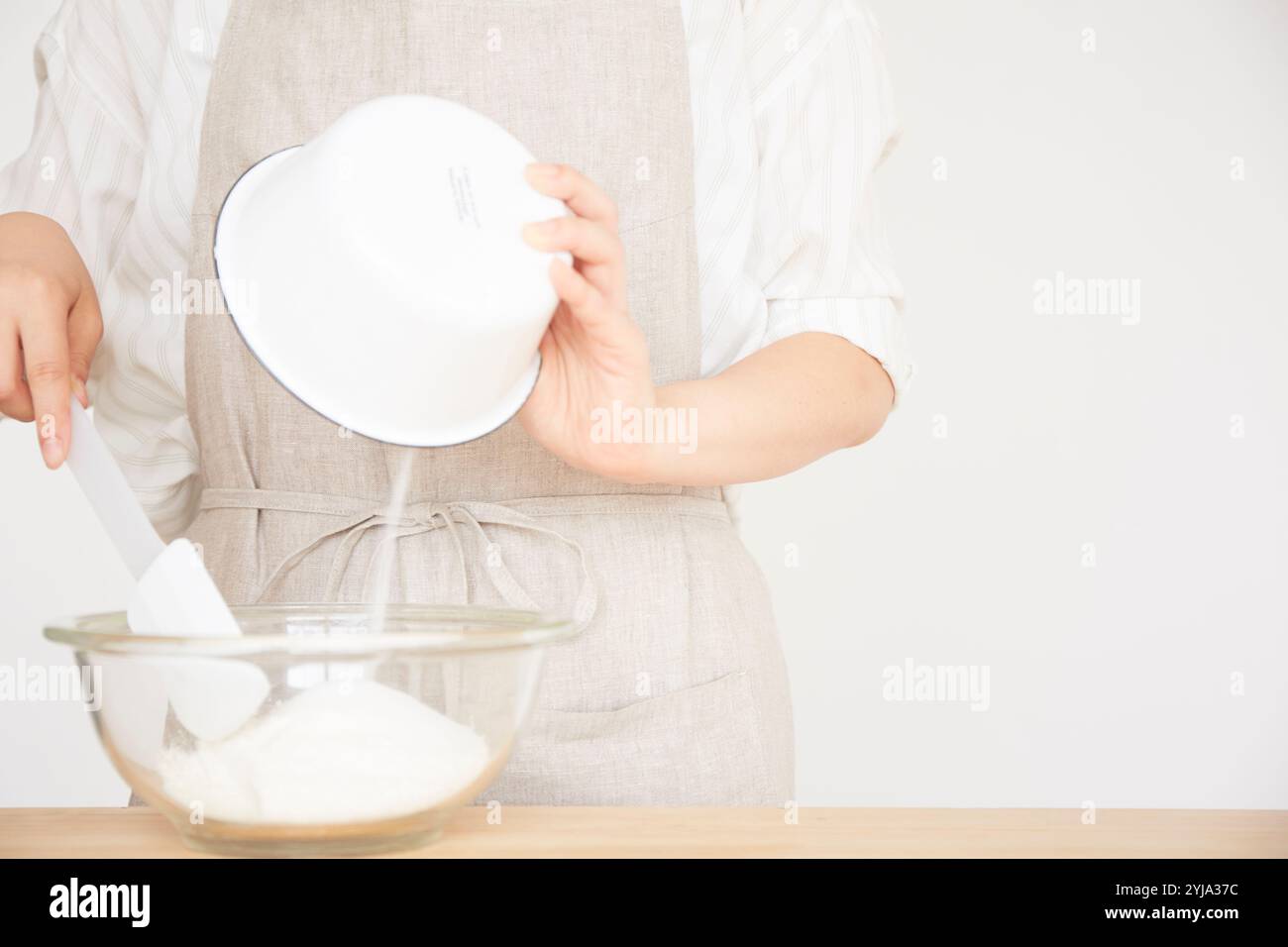 Frau, die Zutaten in eine Schüssel gibt Stockfoto