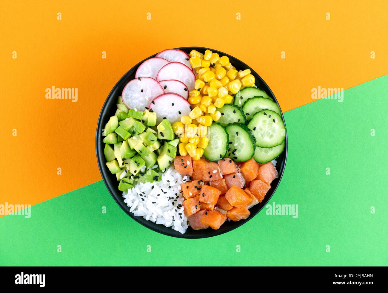 Poke Bowl mit Lachs, Reis, Gurke, Mais, Rettich, Avocado auf orangefarbenem Hintergrund, Draufsicht. Ausgewogene Ernährung. Stockfoto