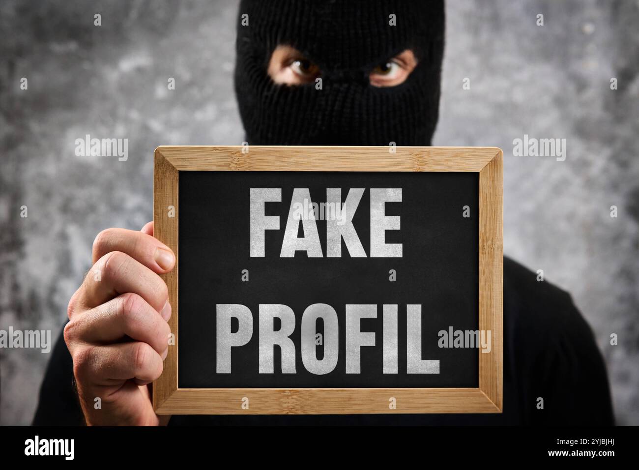 Bayern, Deutschland - 14. November 2024: Gefälschtes Profil oder gefälschtes Profil, stehend auf einem Schild vor einer maskierten anonymen / unbekannten Person. Symbolisches Bild für die falsche Nutzung von Identität im Internet und in sozialen Medien, in Verbindung mit Fotos und Profilbildern von Personen. FOTOMONTAGE *** Fakeprofil bzw. Fake Profil, steht auf einem Schild vor maskierter Anonymer / Unbekannter Person. Symbolbild für falsche Nutzung von Identität im Internet und sozialen Medien, im Zusammenhang mit Fotos und Profil-Bilder von Personen. FOTOMONTAGE Stockfoto