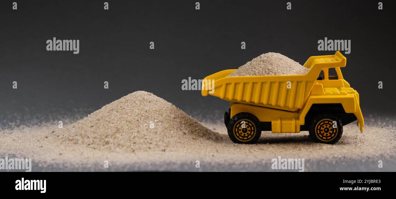 Gelber Muldenkipper auf dunkelgrauem Hintergrund. Schüttgüter, Sand, Ziegel, Splitter, Zement geliefert. Bulk-Baumaterial. Kopierbereich Stockfoto