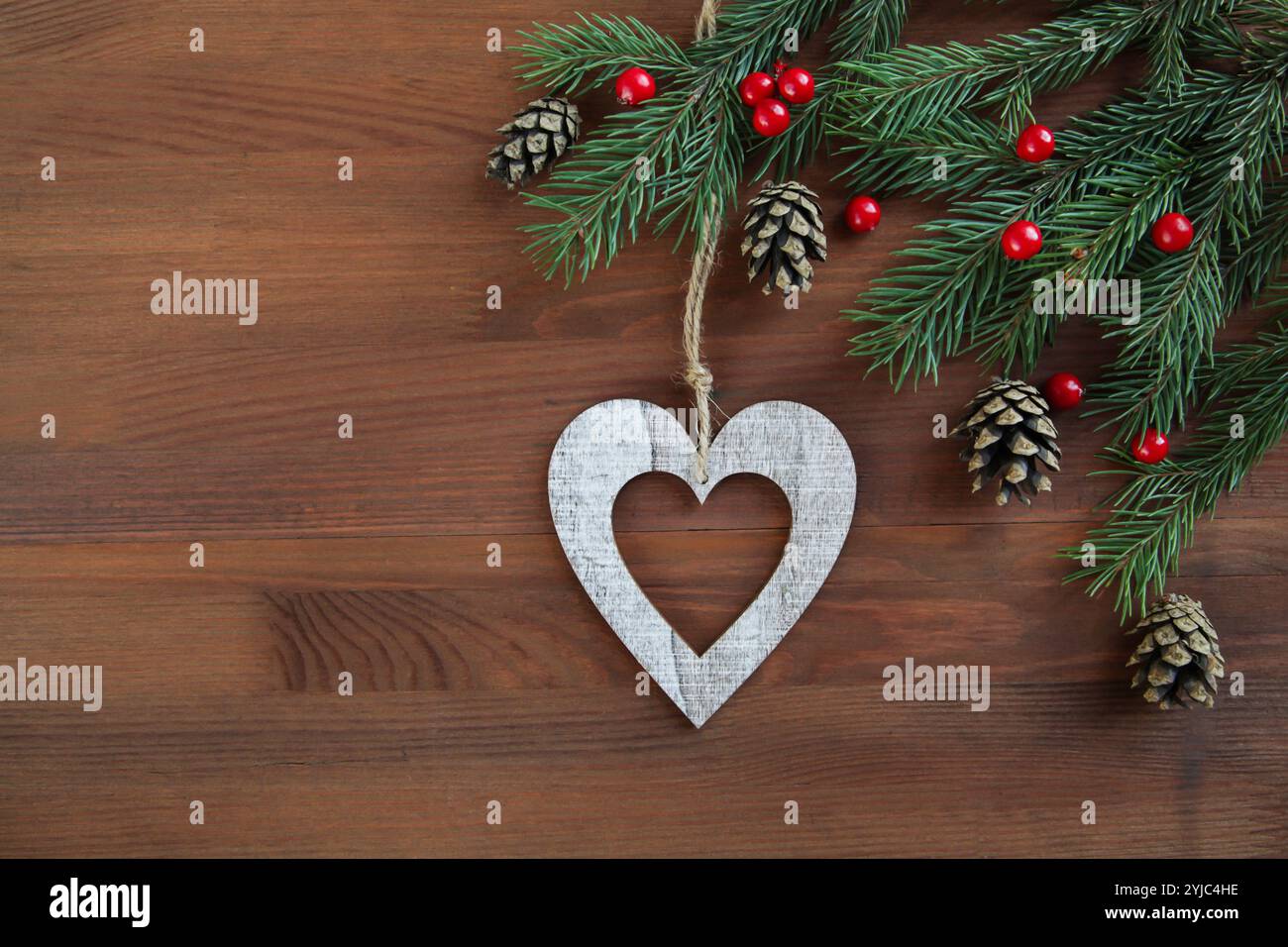 Weihnachtsschmuck hölzernes Herz auf hölzernem Hintergrund. Umweltfreundlicher Naturrahmen. Leerzeichen für Text. Kopierbereich Stockfoto