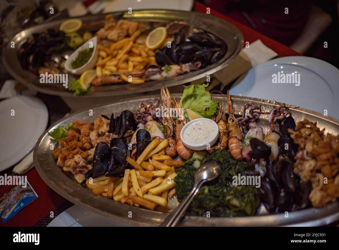 Mediterrane Küche mit Garnelen, Tintenfischen, Muscheln, herzhaften Saucen und knusprigen Pommes frites für ein köstliches Meeresfrüchte-fest. Stockfoto