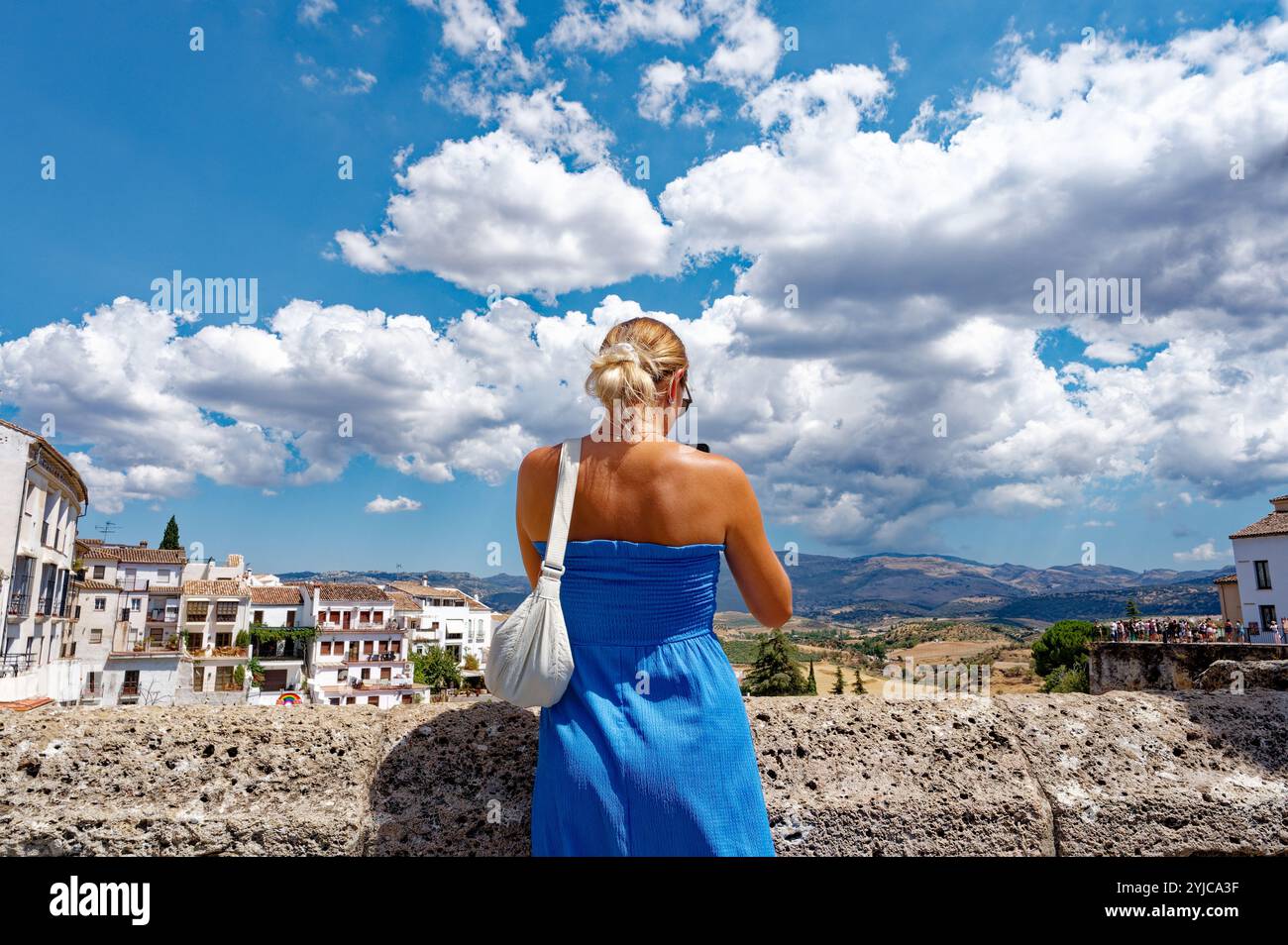 Eine Frau in blauem Kleid genießt die Aussicht auf Rondas Landschaft und den historischen Charme Stockfoto