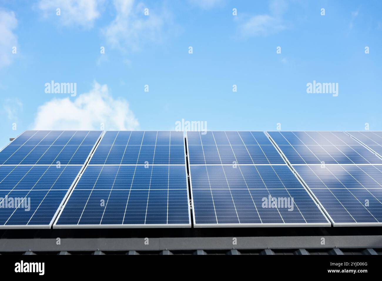 Solarzellen auf wolkenblauem Himmel Hintergrund. Sauberes Konzept für alternative Energie. Modernes Haus mit Solarpaneelen, eigenständige Photovoltaikanlage Stockfoto