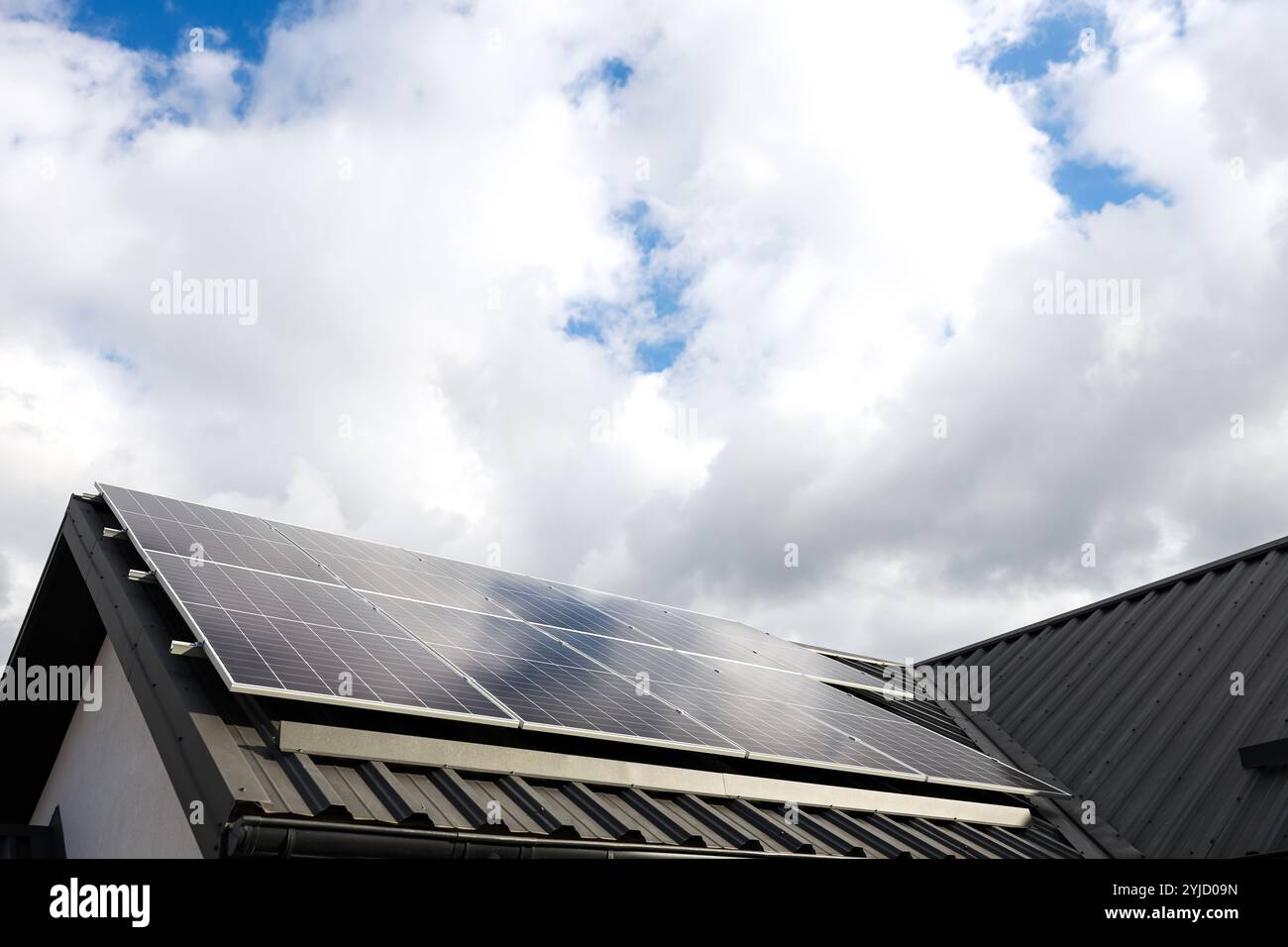 Saubere alternative Energie. Modernes Haus mit Solarpaneelen, eigenständiges Photovoltaik-Anlagensystem auf dem Dach des Haushaltsblechs. Wolken, blauer Himmel zurück Stockfoto