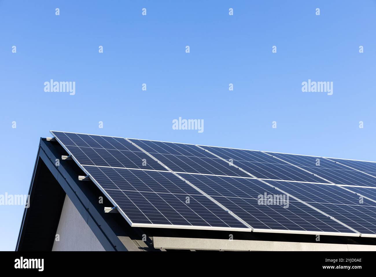 Modernes Haus mit Solarpaneelen, eigenständiges Photovoltaik-Anlagensystem auf dem Dach des Haushaltsblechs. Blauer Hintergrund. Saubere Alternative en Stockfoto