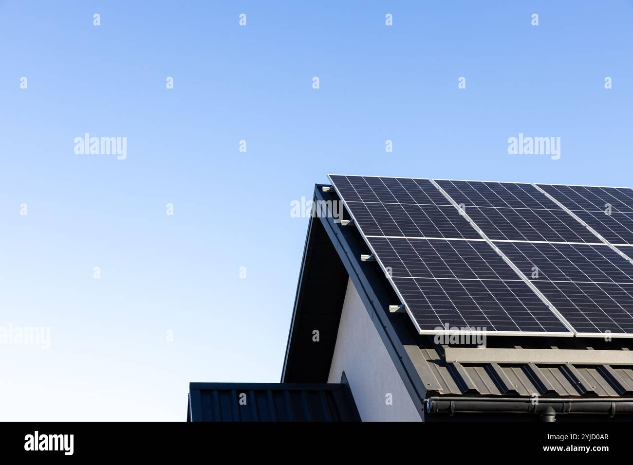 Modernes Haus mit Solarpaneelen, eigenständiges Photovoltaik-Anlagensystem auf dem Dach des Haushaltsblechs. Blauer Hintergrund. Saubere Alternative en Stockfoto