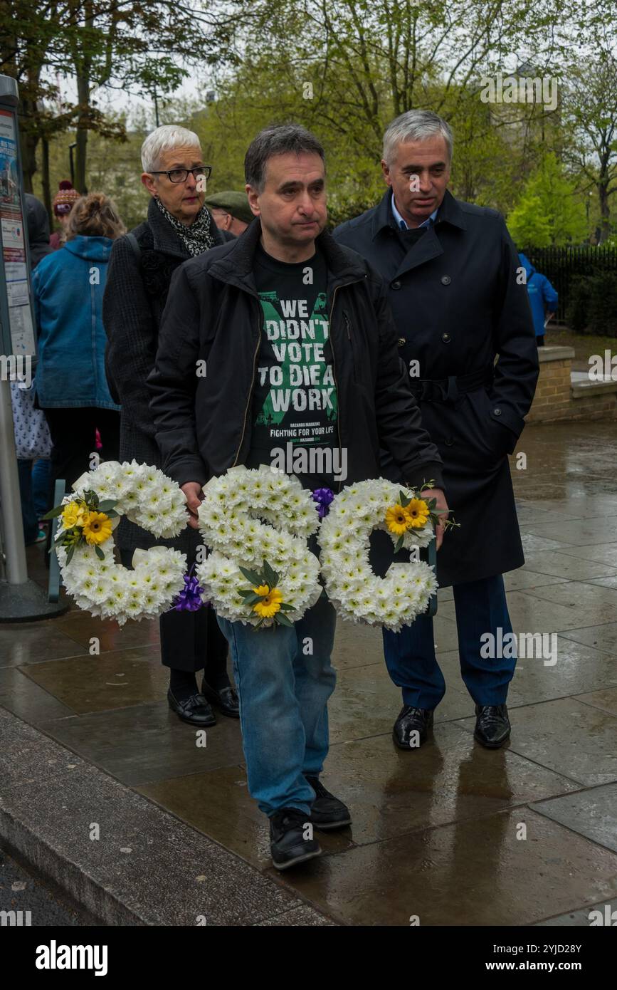 London, Großbritannien. April 2018. Ein Mann legt einen Kranz für die Sicherheitskampagne im Baugewerbe an der Statue eines Bauarbeiters auf Tower Hill, um an all jene zu erinnern, die in den letzten zehn Jahren um 500 Menschen bei der Arbeit getötet wurden, hauptsächlich in der Bauindustrie, sowie an Verletzte, Behinderte und Unwohlsein, fast alle durch vermeidbare Vorfälle. Die tatsächliche Zahl der arbeitsbedingten Todesfälle ist um mehrere Größenordnungen höher, geschätzt auf über 150 pro Tag, aber die offiziellen Zahlen schließen nur diejenigen ein, die tatsächlich am Arbeitsplatz getötet wurden, für die Unfallberichte unterschrieben wurden Stockfoto