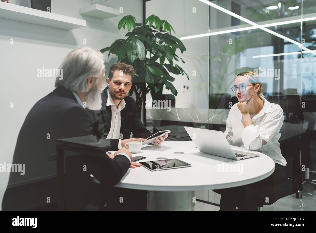 Das Büro ist voll von kaukasischen Geschäftsleuten unterschiedlichen Alters, die an ihren Schreibtischen arbeiten. Kaukasische Geschäftsleute arbeiten in einem neuen modernen Licht Stockfoto