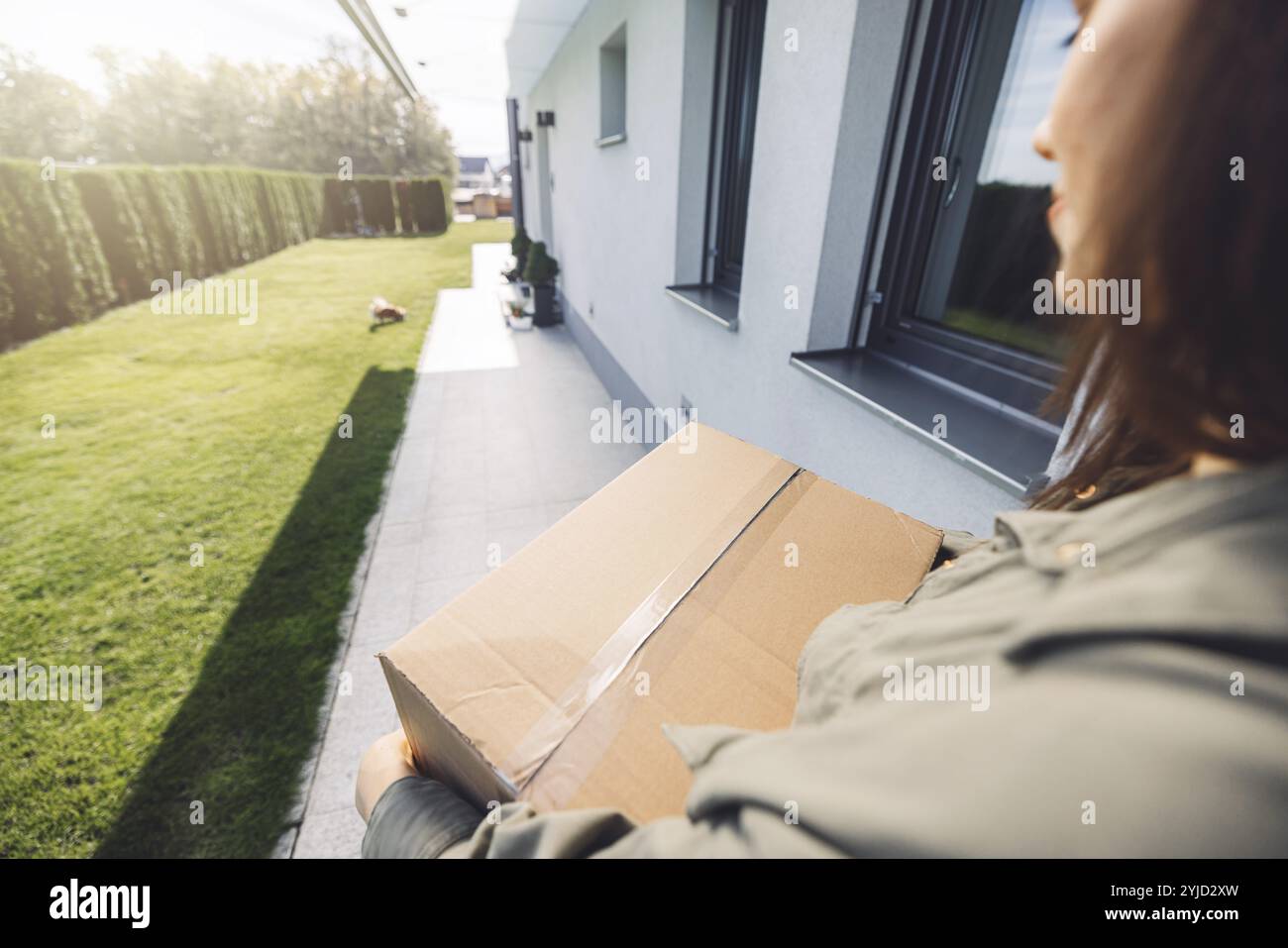 Junge kaukasische Frau erhält eine große Kiste mit ihren Online-Bestellungen. Frau, die das Paket öffnet und begeistert ist, das Zeug zu sehen, das sie gekauft hat. Stockfoto