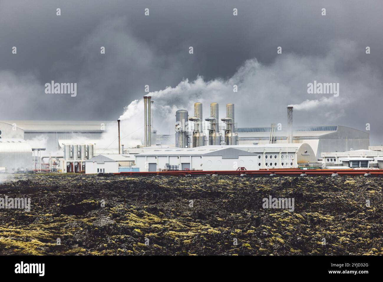 Geothermiekraftwerk, Warmwasserkraftwerk in Island. Dampf, der aus den Schornsteinen der Anlage herausgerollt wird, rote große Rohre, die über das Gelände laufen, gefüllt Stockfoto