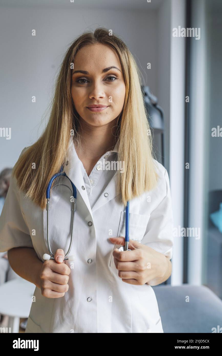 Junge blonde Pflegerin, vertikales Porträt. Stockfoto