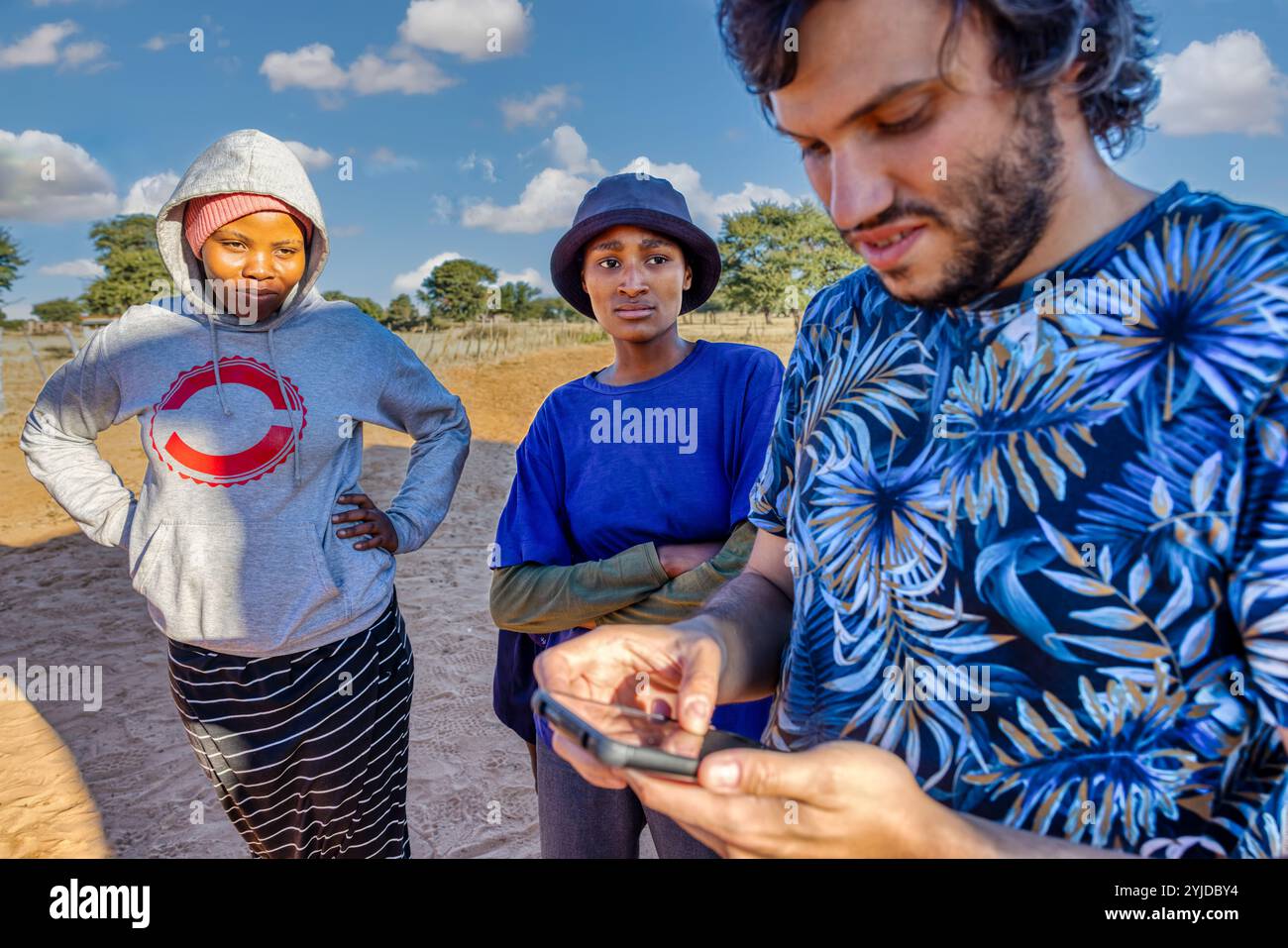 Ehrenamtliche Mitarbeiterin bei einer Wohltätigkeitsorganisation in einem afrikanischen Dorf, die junge Frauen vor Ort in der Nutzung mobiler Apps zur Verbesserung der landwirtschaftlichen Aktivitäten ausbildet Stockfoto