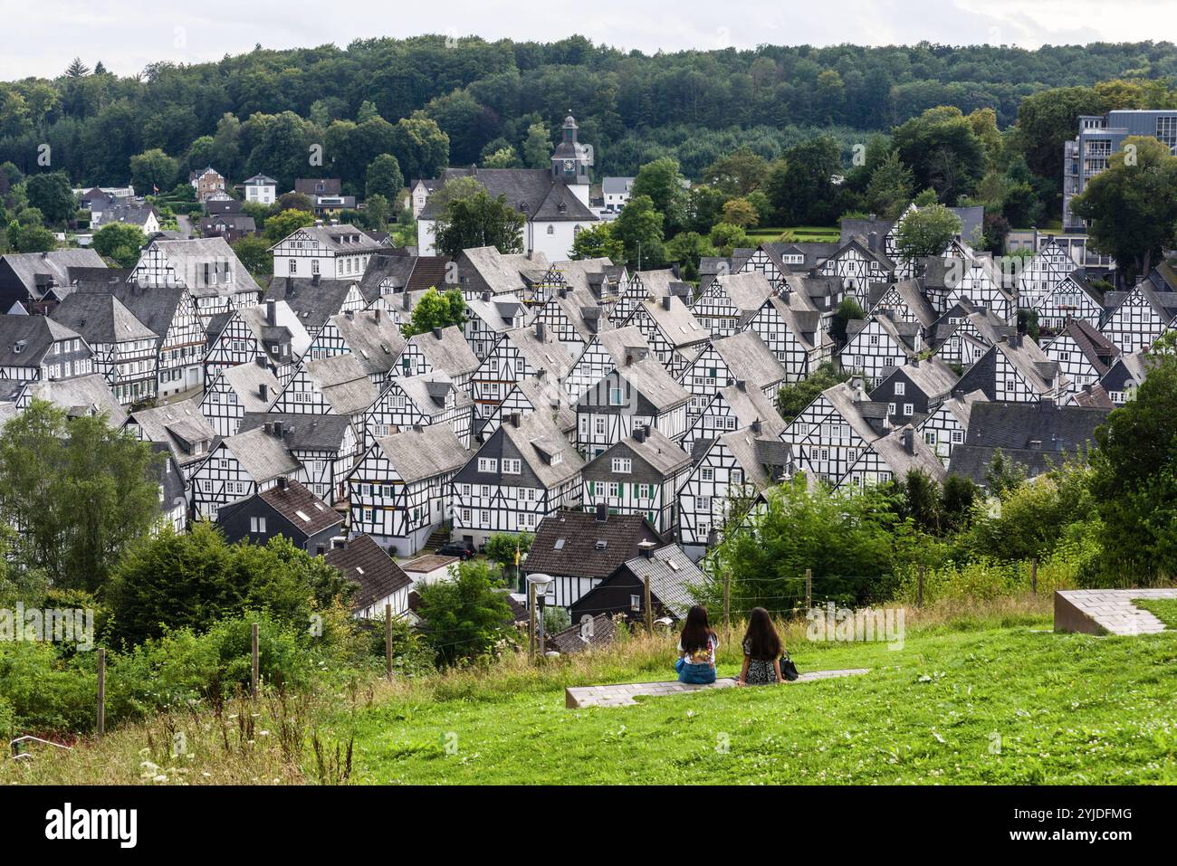 2 Frauen sitzen auf einer Mauer mit Blick auf den historischen Ortskern Alter Flecken mit seinen markanten Fachwerkbauten in Freudenberg, Kreis Siegen-Wittgenstein, Nordrhein-Westfalen, Deutschland. Fachwerkhäuser in Freudenberg *** 2 Frauen auf einer Mauer mit Blick auf die historische Altstadt von Alter Flecken mit ihren markanten Fachwerkhäusern in Freudenberg, Landkreis Siegen Wittgenstein, Nordrhein-Westfalen, Deutschland Fachwerkhäuser in Freudenberg Stockfoto