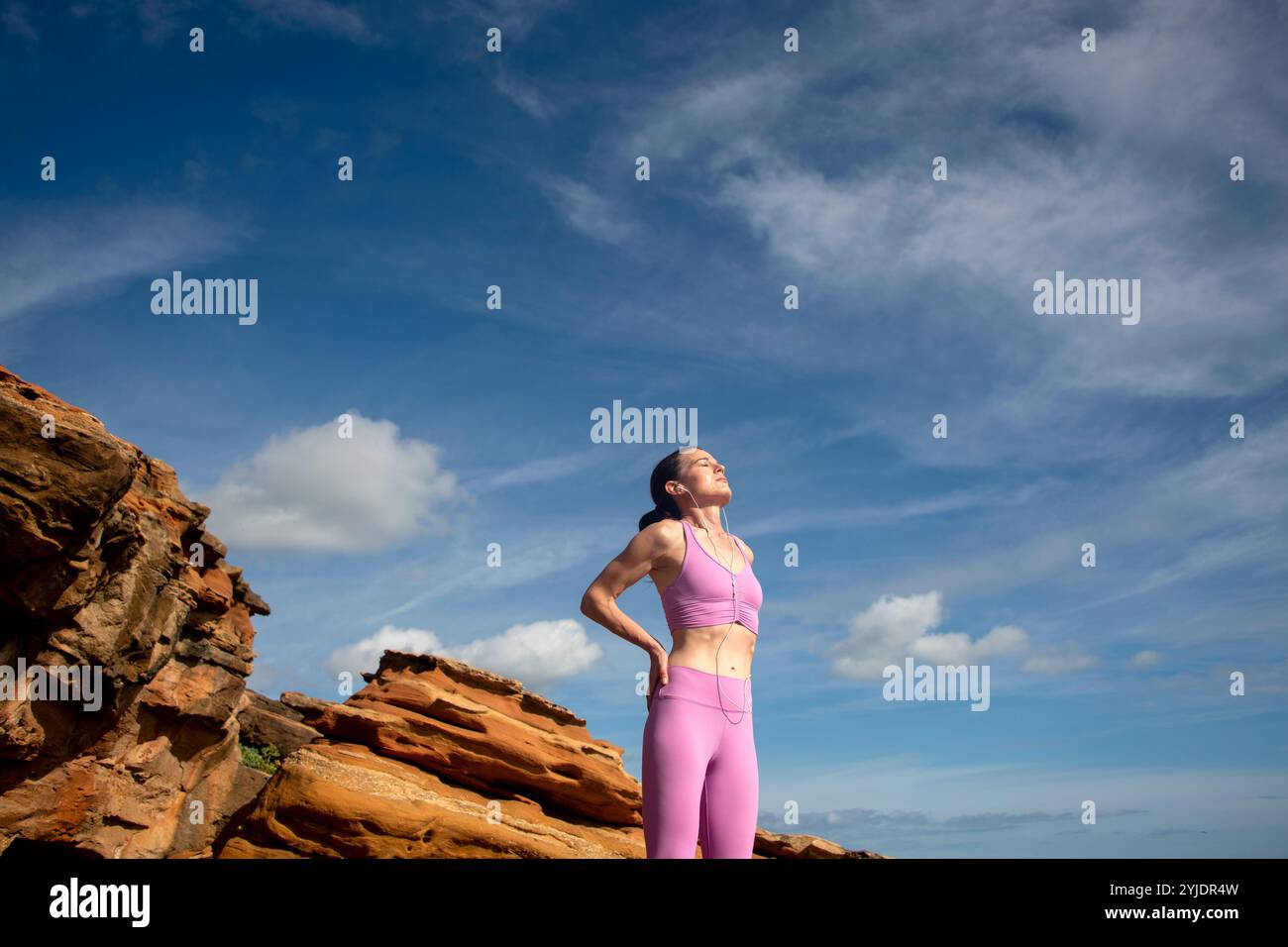 Sportliche Frau, die die Sonne genießt, sich nach dem Training ausruht und Vitamin D erhält Stockfoto
