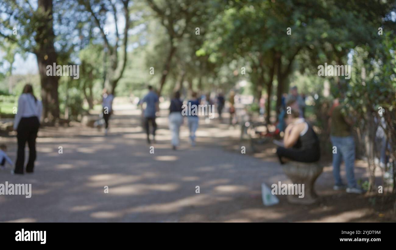 Menschen laufen in den verschwommenen Gärten der Villa borghese, in denen das Sonnenlicht durch die Bäume strömt, und Männer und Frauen in einer Umgebung im Freien in rom sehen. Stockfoto