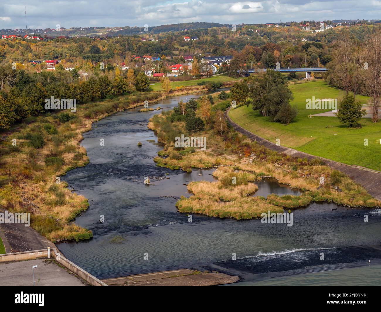 Ein malerischer Fluss schlängelt sich durch eine üppige Herbstlandschaft mit lebhaftem Laub und malerischen Häusern Stockfoto