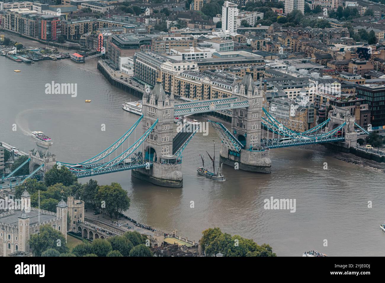 Ein Boot mit hohem Mastmast unterquert die erhöhte Tower Bridge, die 1894 fertiggestellt wurde und eines der bekanntesten Wahrzeichen Londons ist, City of London, UK Stockfoto
