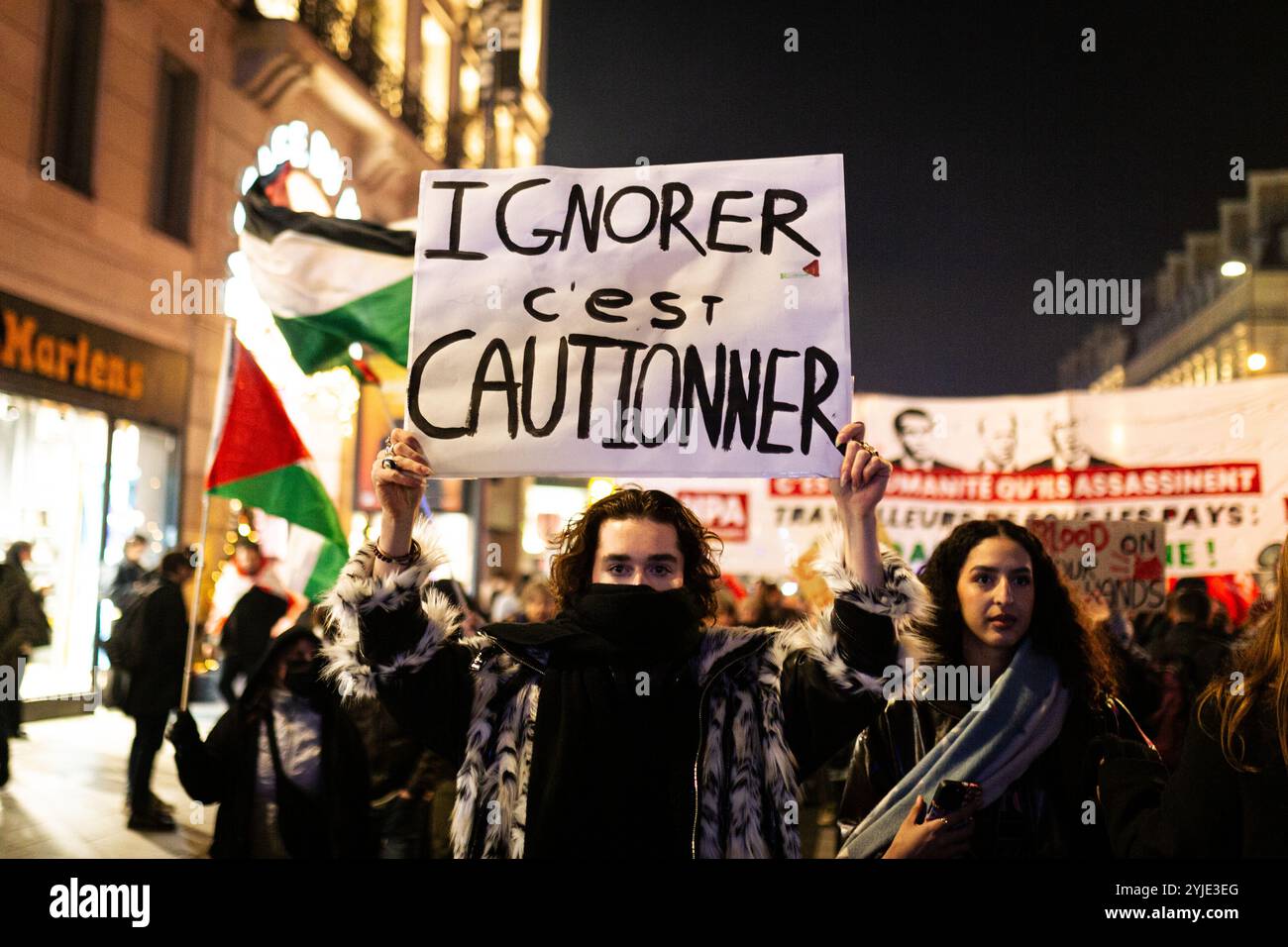 Während der pro-palästinensischen Demonstration gegen die Organisation der pro-israelischen Gala "Israel ist für immer" in Paris hält ein Mann ein Plakat mit der Aufschrift "zu ignorieren heißt zu dulden". Tausende von Menschen demonstrierten in Paris gegen die Gala, die von der extremen Rechten zur Unterstützung Israels organisiert wurde: „Israel ist für immer“. Stockfoto