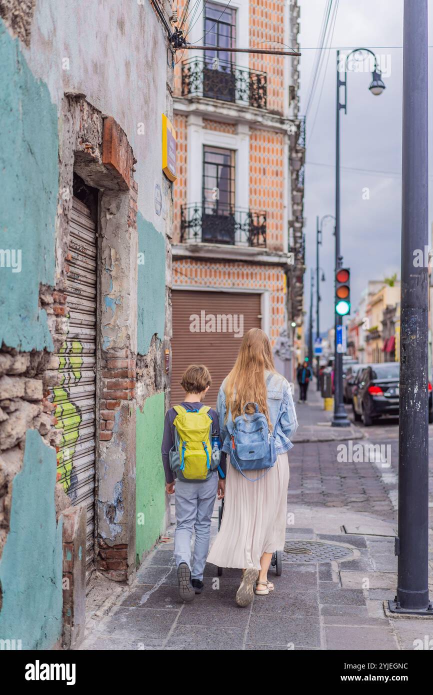 Mutter Tourist mit ihrem Kleinkind und ihren Söhnen im Teenageralter spazieren durch die farbenfrohen Kolonialstraßen von Puebla, Mexiko. Reisen, kulturelle Entdeckungen und Stockfoto