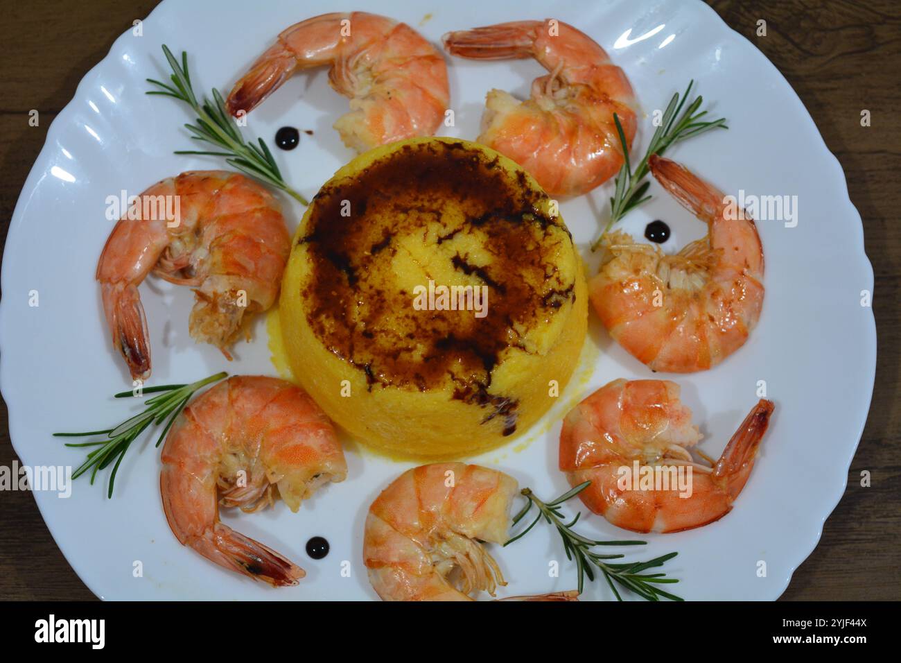 Hauptgericht mit Garnelen, Polentasauce und Rosmarinzweigen, sehr lecker in der Küche Stockfoto