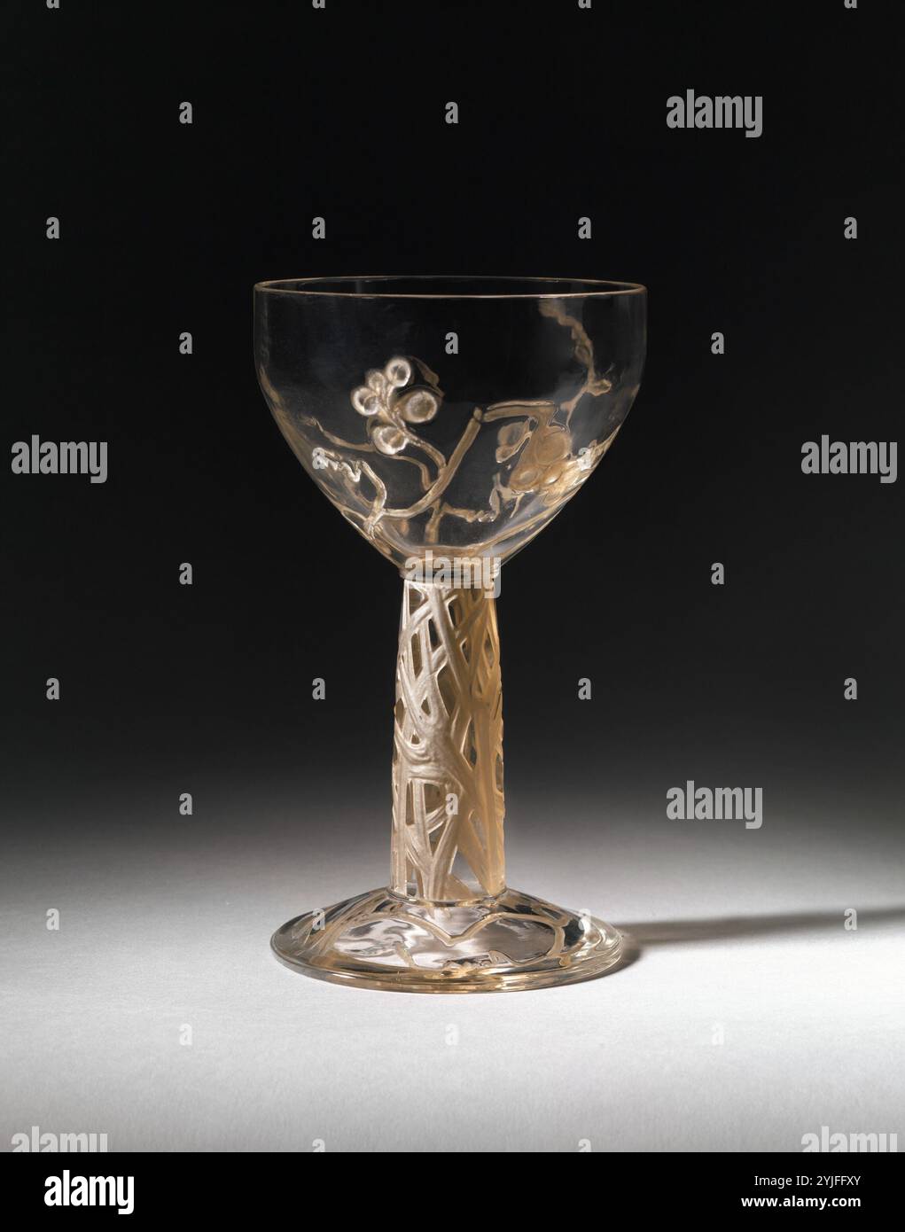 „Vigne“ (Vine) Cup. Kultur: Französisch. Designer: René-Jules Lalique (Französisch, Aÿ 1860-1945 Paris). Abmessungen: H 7, Durchm. 4 Zoll (17,8 x 10,2 cm). Hersteller: René-Jules Lalique (Französisch, Aÿ 1860-1945 Paris). Datum: 1912. Laliques berufliche Laufbahn lässt sich in Hälften unterteilen: Die erste, von etwa 1880 bis etwa 1907, als er sich seinen Ruf als einer der renommiertesten Pariser Juweliere erwarb; die zweite, bis zu seinem Tod im Jahr 1945, als er sich der Glasgestaltung zuwandte. In beiden Bereichen gilt er als einer der bedeutendsten Designer des 20. Jahrhunderts. Museum: Metropolitan Stockfoto