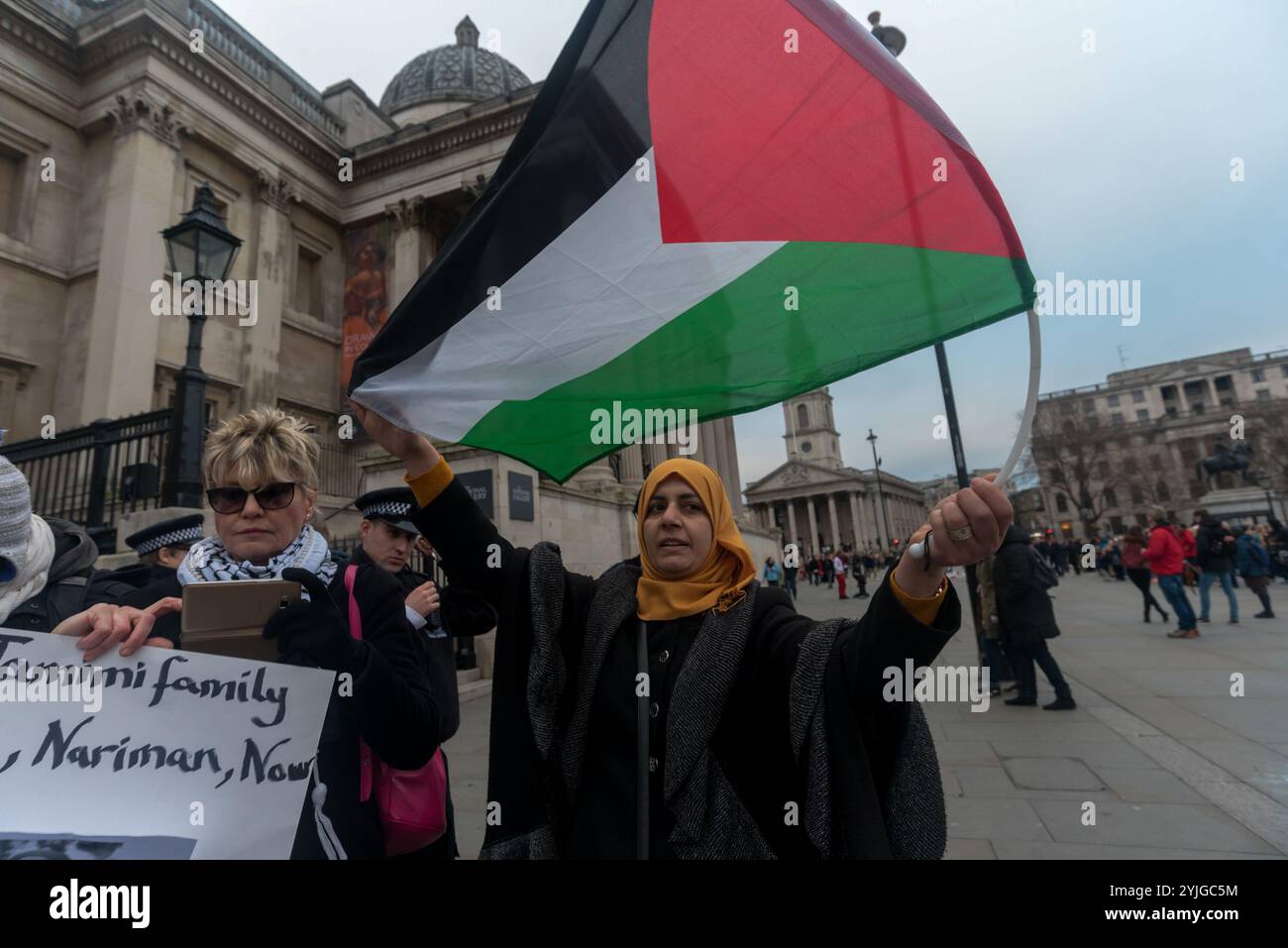 London, Großbritannien. 23. Dezember 2017. Eine Frau hält eine palästinensische Flagge beim Protest auf dem Trafalgar-Platz gegen die Entführung, indem sie am Dienstag, den 19. Dezember, um 4 Uhr morgens die 16-jährige Ahed Tamimi von israelischen Soldaten in ihrem Haus verprügelt und verhaftet und ihre Mutter Nariman Tamimi und ihre Cousine Nour Tamimi verhaftet, um ihre sofortige Freilassung zu fordern. Die beiden jüngeren Frauen hatten zuvor israelische Soldaten in ihrem besetzten Dorf Nabi Saleh geschlagen, als ihr 14-jähriger Cousin von israelischen Soldaten ins Gesicht geschossen wurde. Nachdem der Protest einige Zeit vergangen war, kamen zwei Männer an und versuchten, zu hetzen Stockfoto