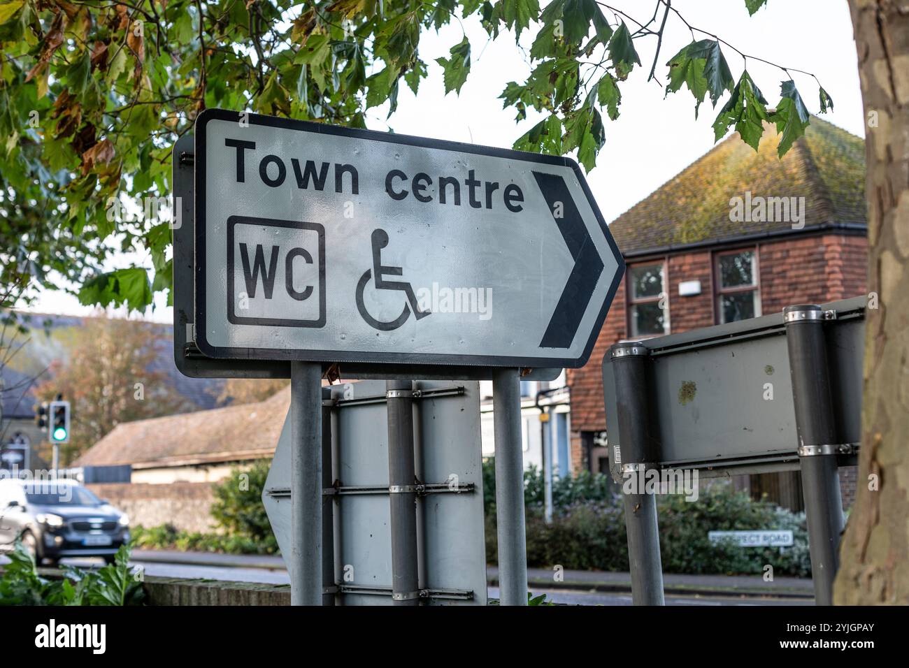 Ein schmutziges Schild zum Stadtzentrum und behindertengerechten Toiletten. Stockfoto