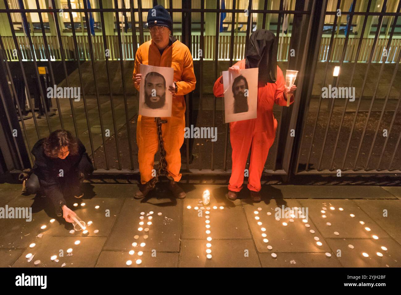 London, Großbritannien. Januar 2018. Die US-Botschaft feierte den 16. Jahrestag des illegalen Folterlagers in Guantanamo Bay, in dem noch 41 Gefangene festgehalten werden, die hauptsächlich auf unbestimmte Zeit ohne Anklage oder Gerichtsverfahren festgehalten werden und die meisten mit dauerhaften Verletzungen durch Folter, die ihre Freilassung für die US-Behörden (und möglicherweise Großbritannien) peinlich machen würden. Die Demonstranten zündeten vor dem Botschaftszaun Kerzen an, in denen sie „GITMO“ schrieben, und standen dann mit Kerzen und großen Fotos der 41 verbliebenen Häftlinge, die meisten zeigten sie vor mehr als zehn Jahren zu Beginn ihrer illegalen Haft Stockfoto