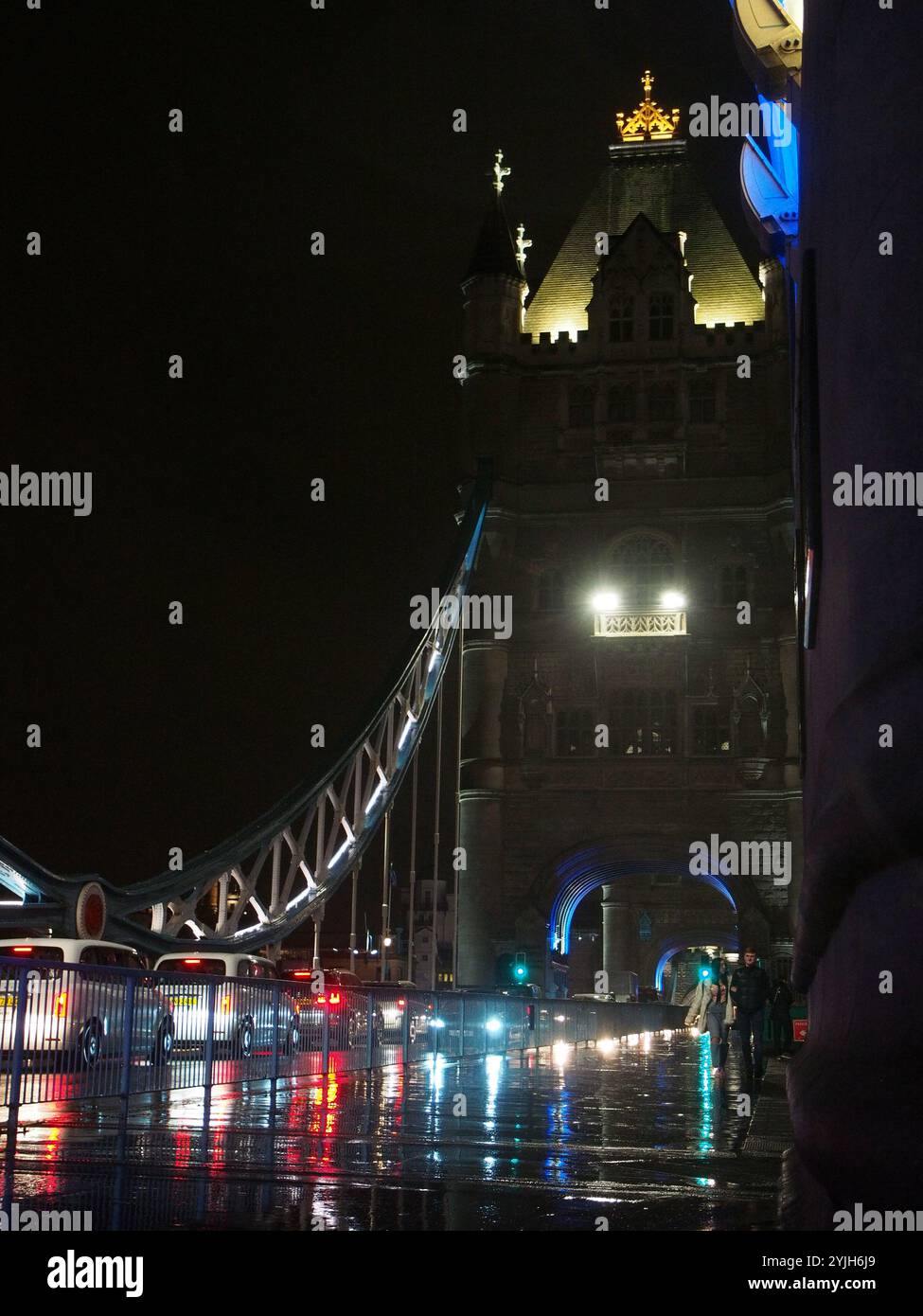 Autos und Fußgänger im Regen auf der Tower Bridge bei Nacht in London, Großbritannien. Konzept: Stadtverkehr, Verkehrsstaus, regnerisches London Stockfoto