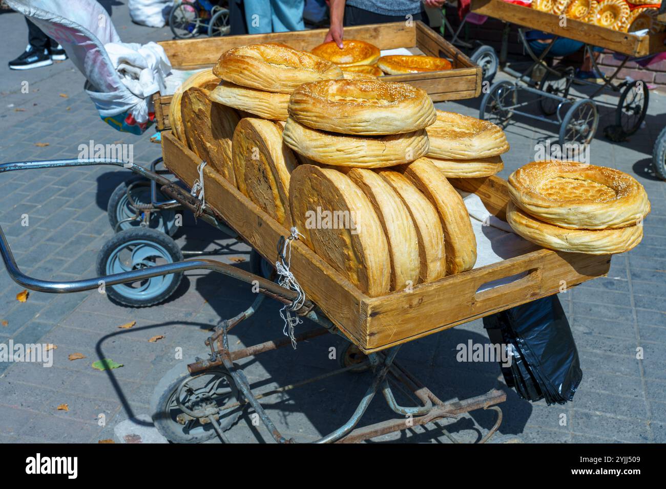 Ein Wagen voller Brot wird die Straße runter geschoben Stockfoto
