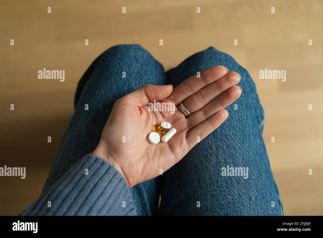 Abgeschnittene Ansicht einer Frau, die mit einer Handfläche voller Pillen sitzt Stockfoto