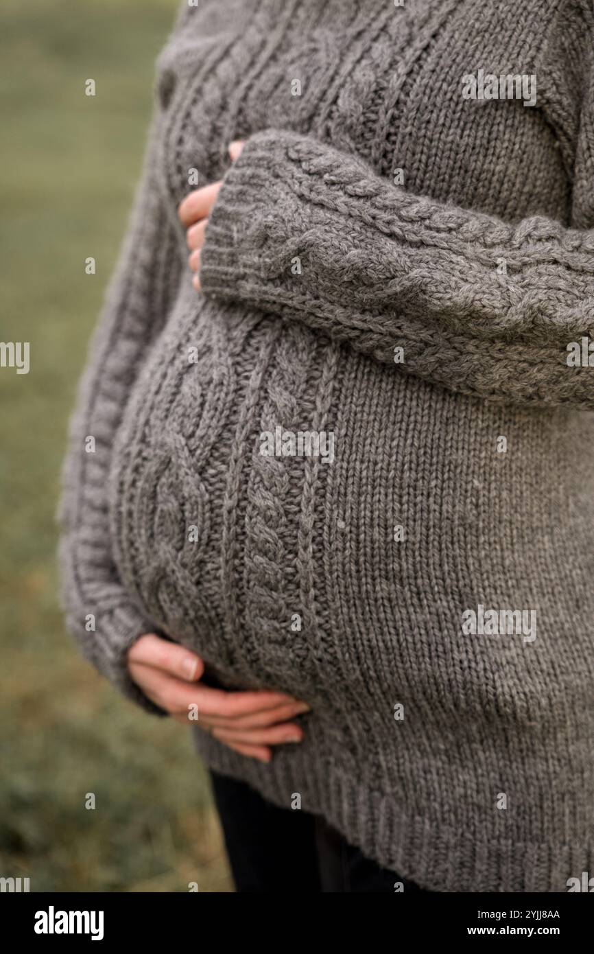 Schwangere Frau in Strickpullover, die Baby Bump hält Stockfoto