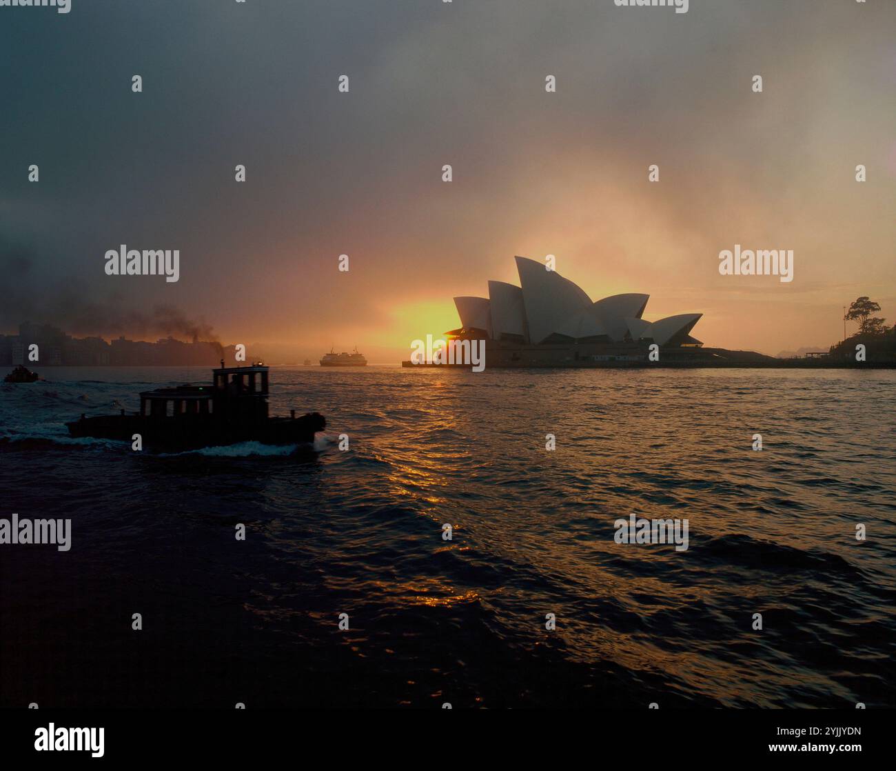 Australien. Sydney. Opernhaus. Bewölkter Sonnenaufgang mit Booten. Stockfoto